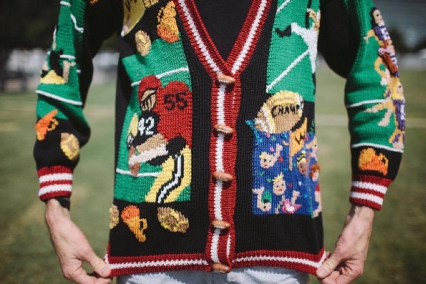 Colorful knitted sweater with sports-themed patterns worn by a person outdoors.