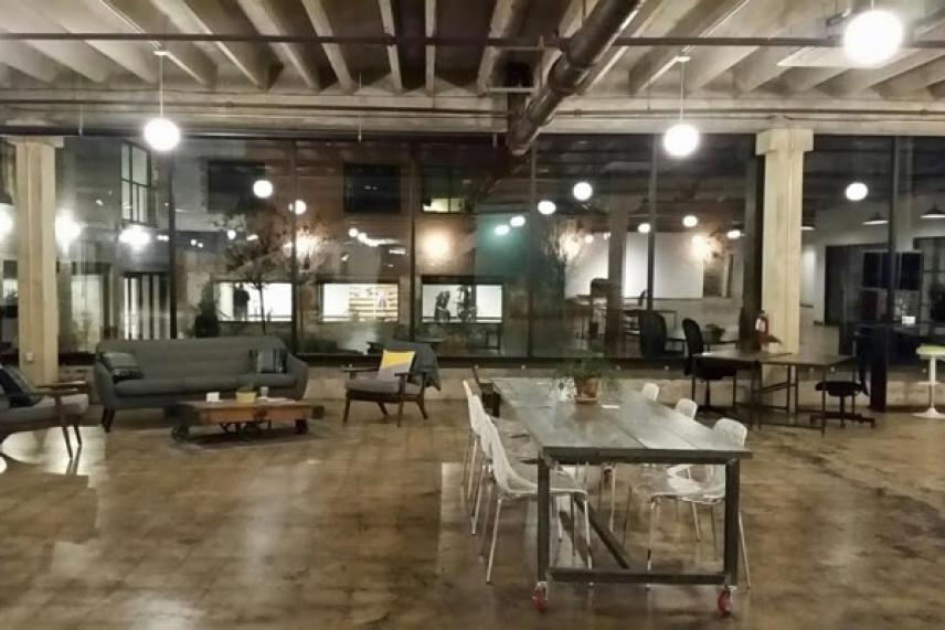 Spacious loft with industrial decor, sofas, and a large table.