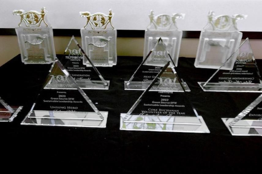 Transparent triangular and rectangular trophies arranged on a black tablecloth.