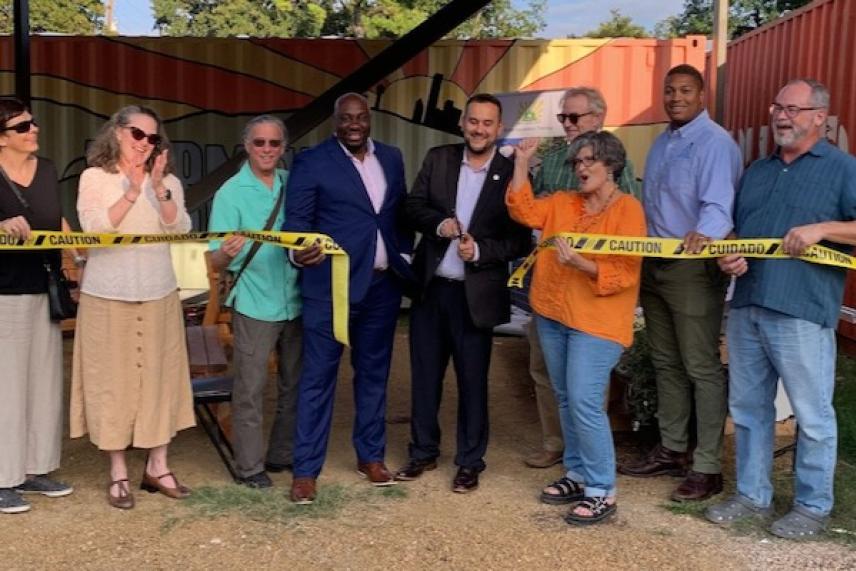 Ribbon-cutting ceremony with a group of smiling people outdoors.
