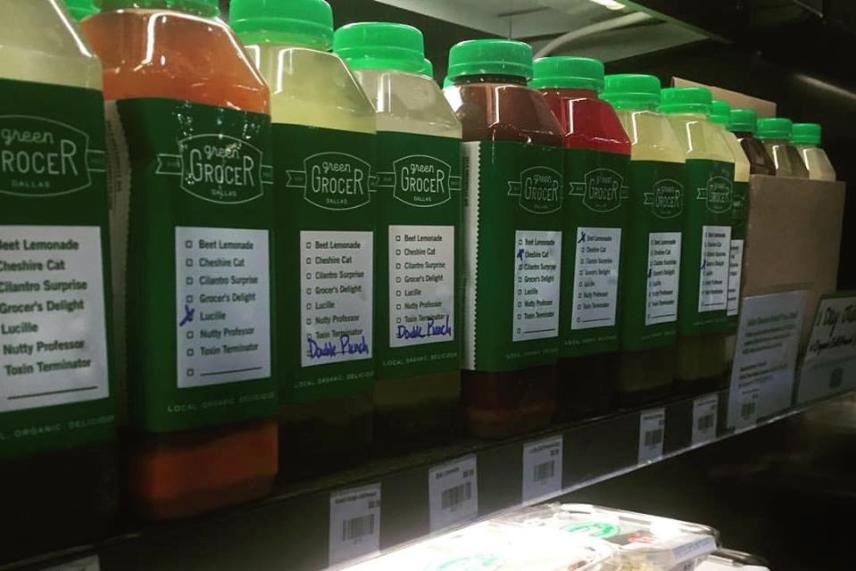 Juice bottles with green caps on a shelf, each labeled with different flavors.