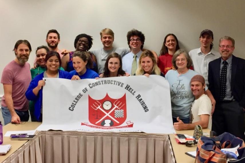 Group of people smiling, holding a white banner with a red and black logo.