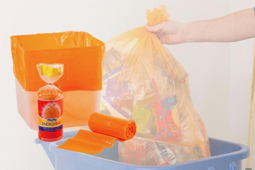 Orange trash bags in use, with a hand placing one into a bin.