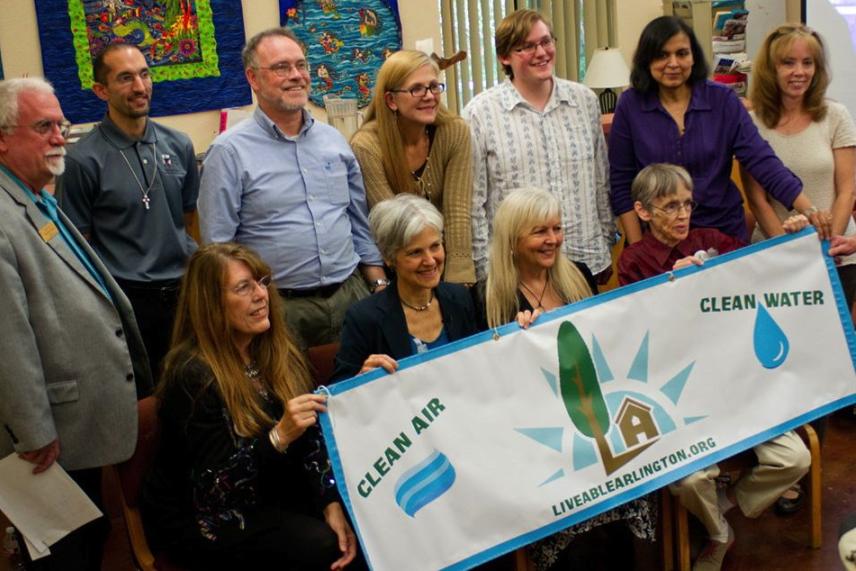 Group of people smiling, holding a banner about clean air and water.