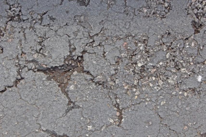 Cracked asphalt with scattered gravel.