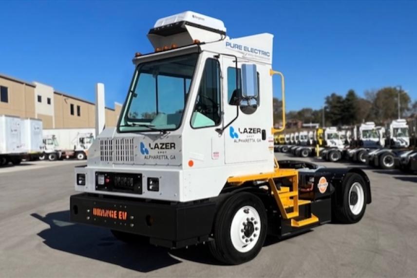 Electric truck parked on asphalt under clear blue sky.