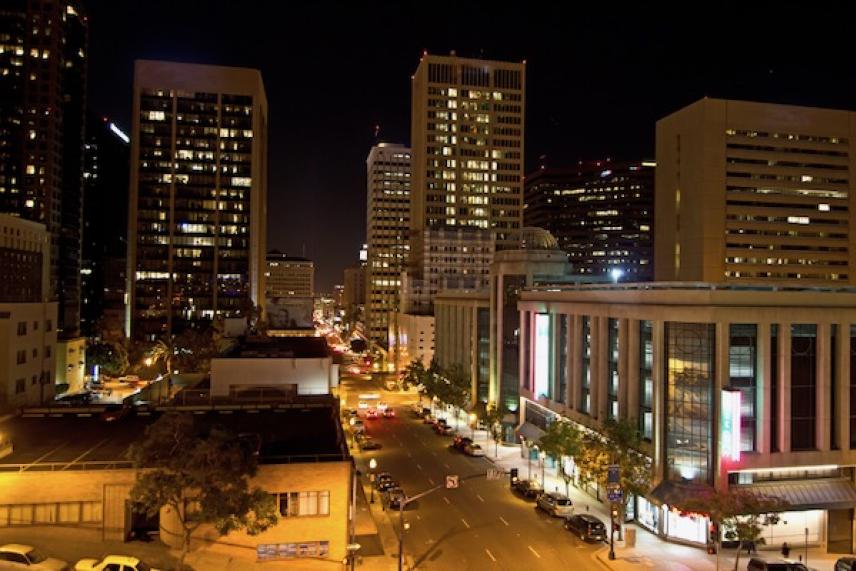 City street at night with tall buildings and lit windows.