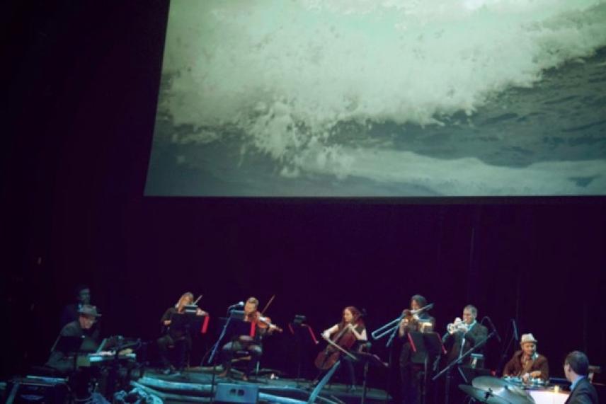 Orchestra performing under a wave projection.