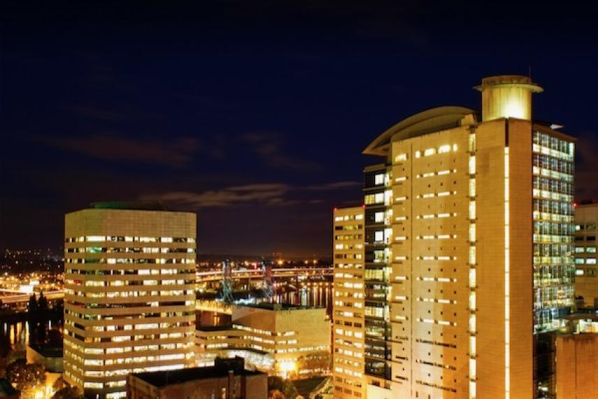 Cityscape at night with illuminated high-rise buildings.