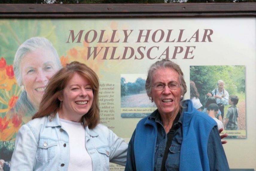 Two people smiling in front of a sign at Molly Hollar Wildscape.