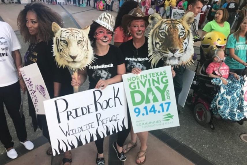 People holding tiger masks and signs at a crowded outdoor event.