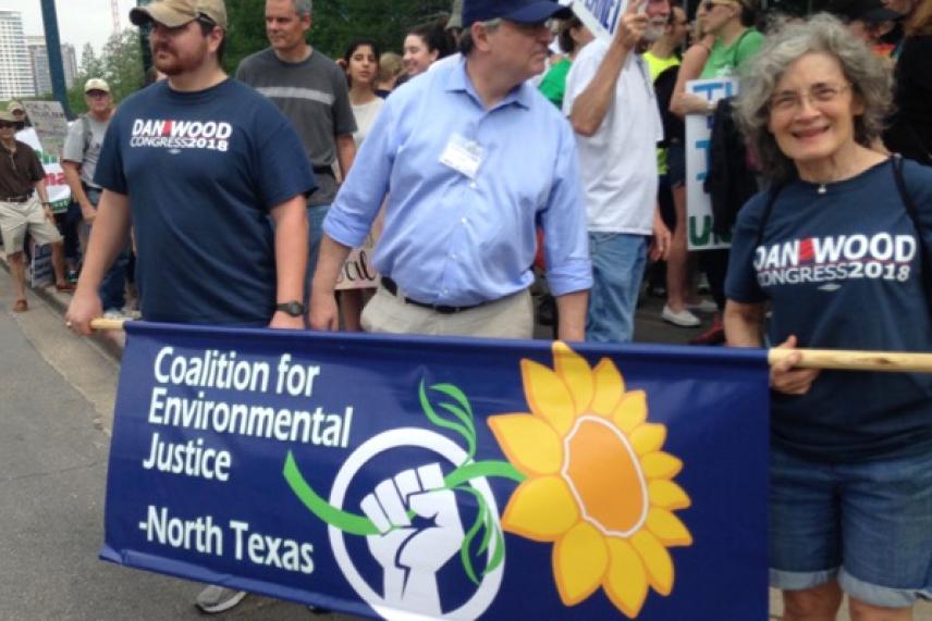 Three people hold a banner for environmental justice during a protest march.