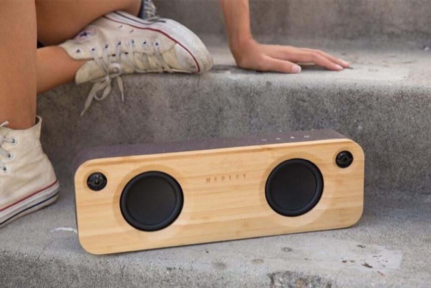 Wooden speaker on stone steps near a person wearing white sneakers.