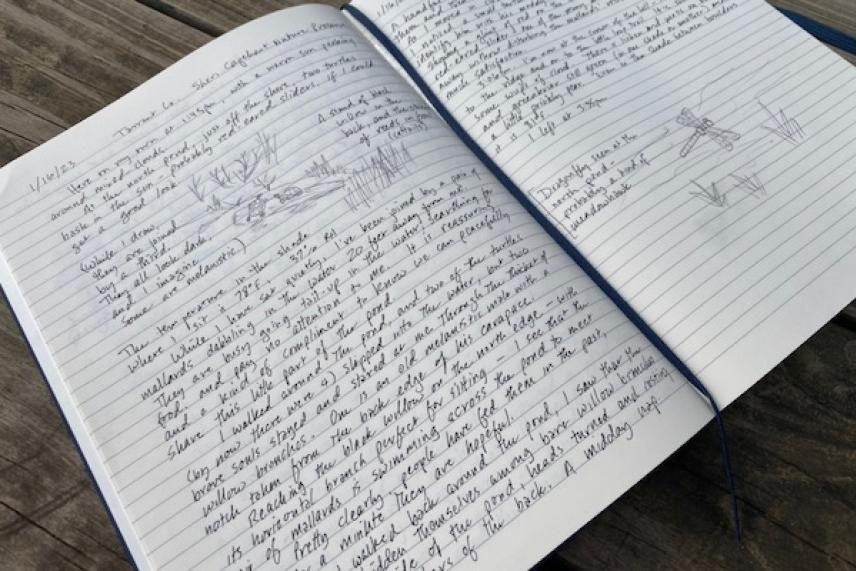 Open notebook with handwritten notes and sketches on wooden table.
