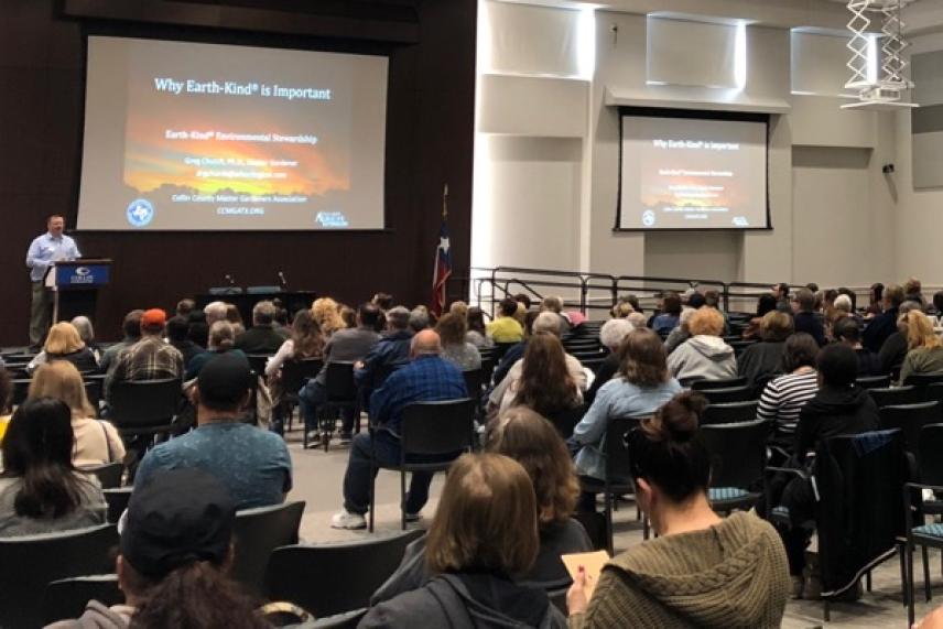 Audience listens to a presentation in a large lecture hall.