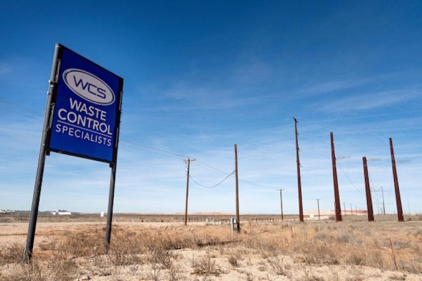 Waste Control Specialists sign in a barren, desolate landscape under a clear blue sky.