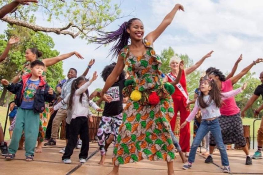 People dancing joyfully outdoors on a sunny day.