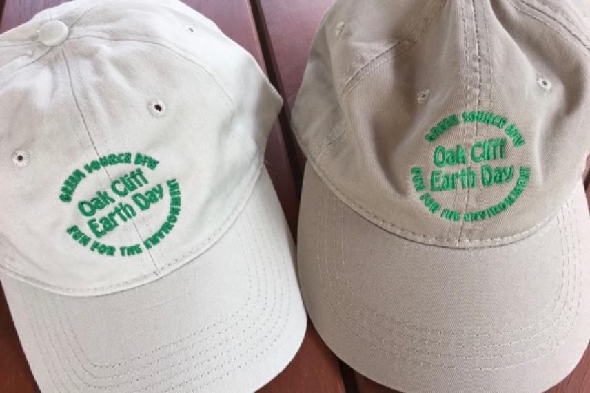 Two beige baseball caps with green embroidered text on a wooden surface.