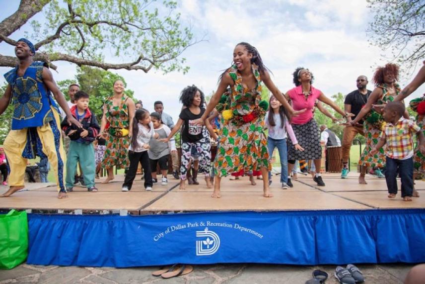 Dancers in colorful attire perform energetically on an outdoor stage.