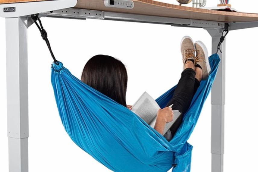 Under-desk hammock with person reading and relaxing.
