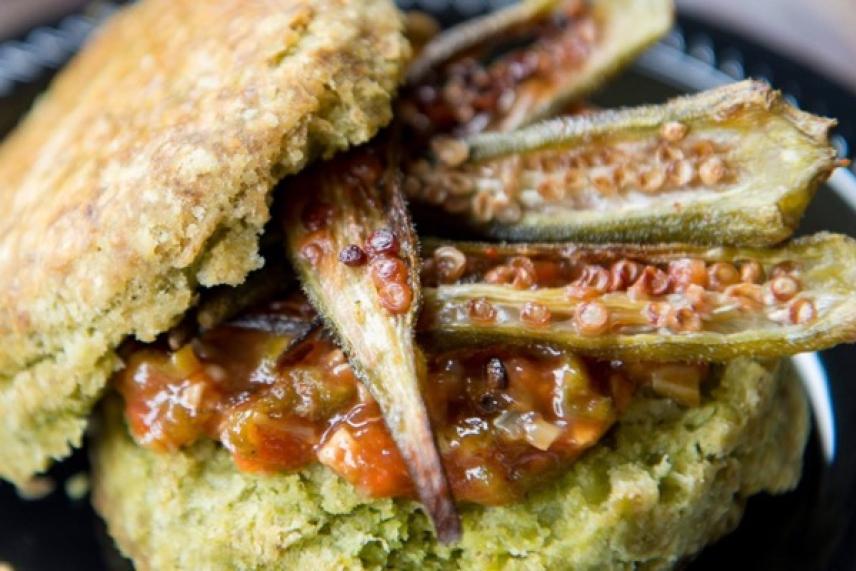 Split okra with biscuit and sauce on a black plate.
