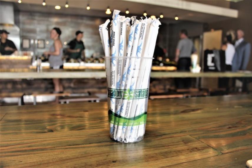 Bundle of wrapped straws on a wooden table in a coffee shop.
