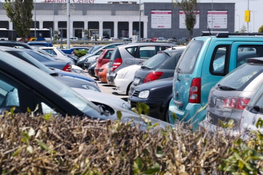 Cars parked in a busy parking lot near a building.
