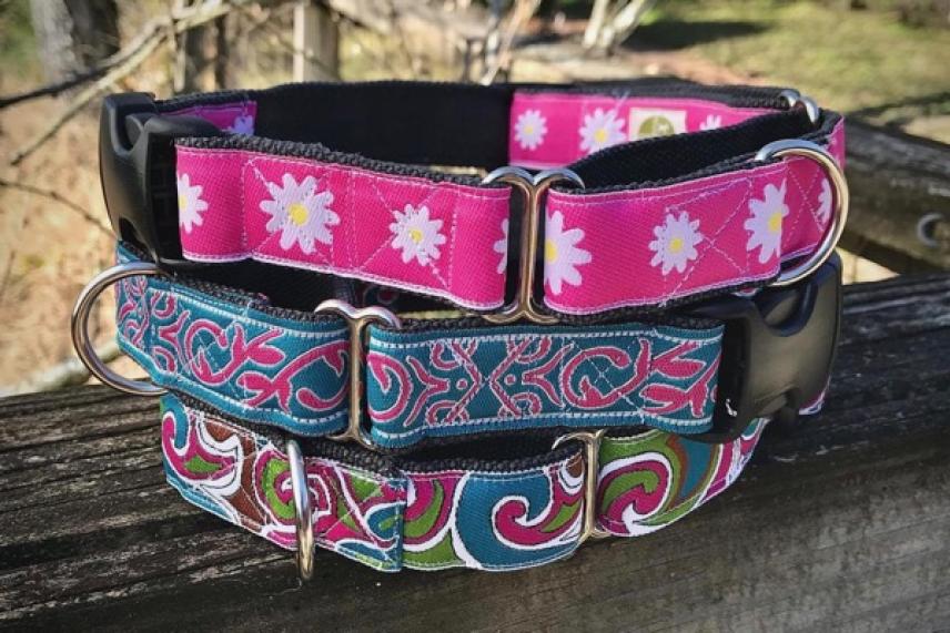 Colorful dog collars with floral and paisley patterns on a wooden surface.