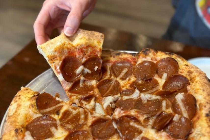Pepperoni pizza slice being lifted from the pan.