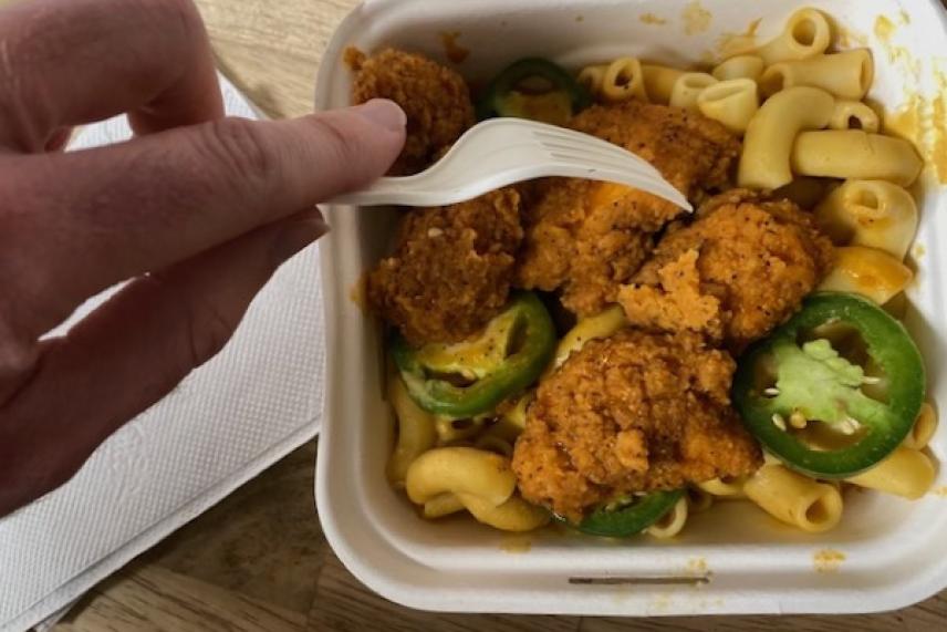 Fried chicken and jalapeños on mac and cheese in a to-go container.
