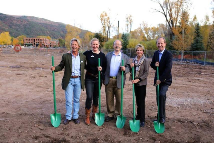 Group photo of five people holding green shovels at a groundbreaking ceremony.
