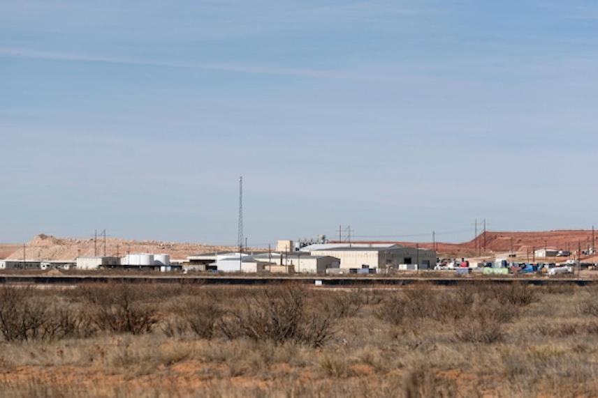 Industrial buildings in a desert landscape under a clear blue sky.