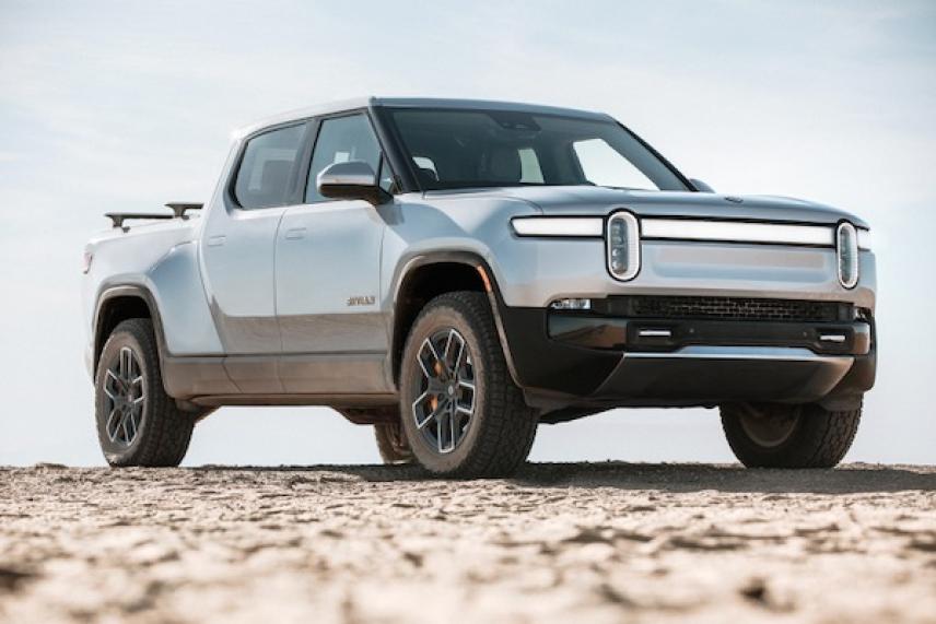 Silver pickup truck on sandy terrain under clear sky.