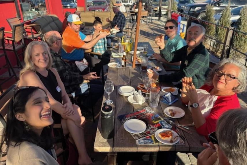 Friends enjoying a meal at an outdoor table, laughing and talking.