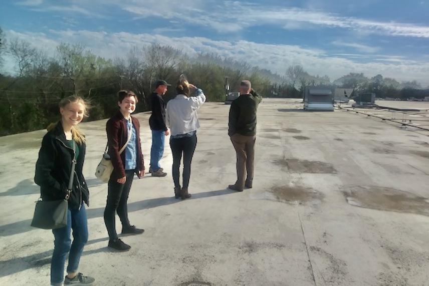 Group walking on a rooftop under a blue sky.
