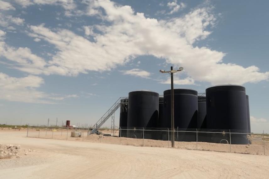 Large black storage tanks under a partly cloudy sky.