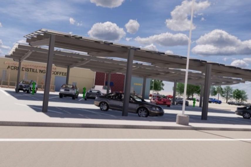 Parking lot with solar panel canopy, several cars, and a clear sky.