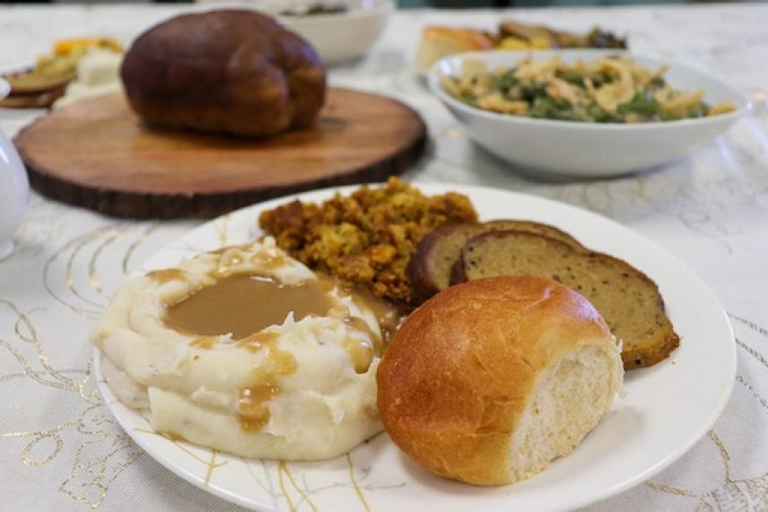 Thanksgiving meal with mashed potatoes, stuffing, and bread on a plate.