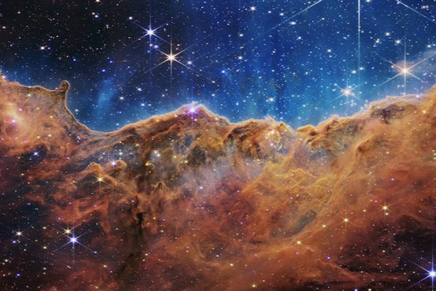 Star-filled galaxy with bright blue and orange swirling nebulae.