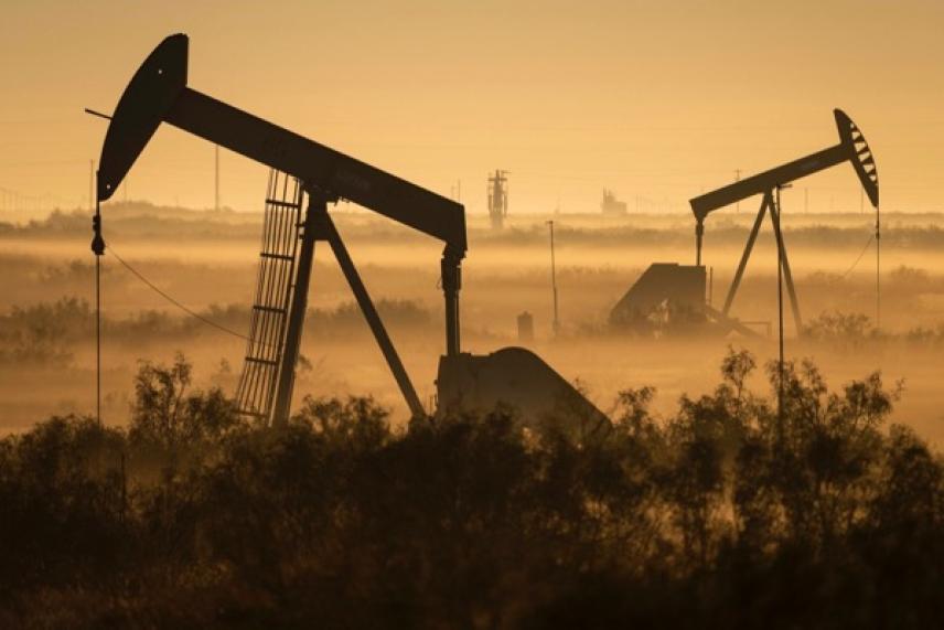 Oil pumps silhouetted against a golden, misty landscape.