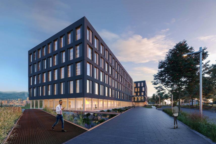 Modern building at dusk with walkway and trees nearby. Sky has scattered clouds.