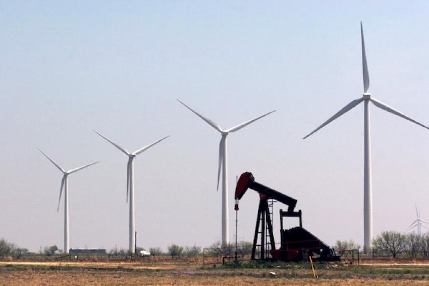 Wind turbines and an oil pump in a field under clear sky.