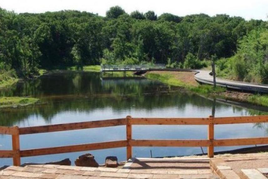 Wooden fence overlooking a calm river surrounded by lush greenery.