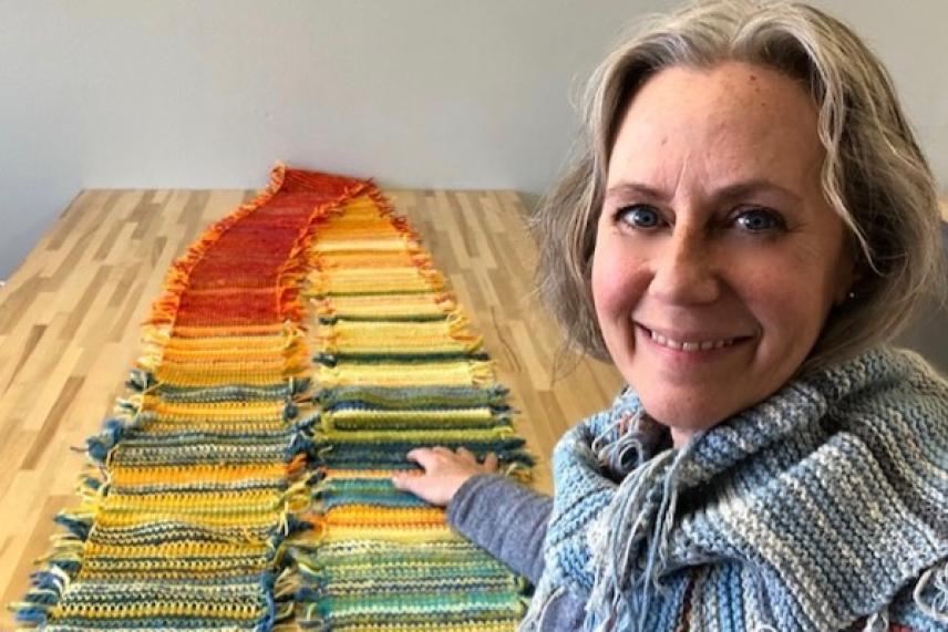Smiling woman with colorful knitted scarf on table.