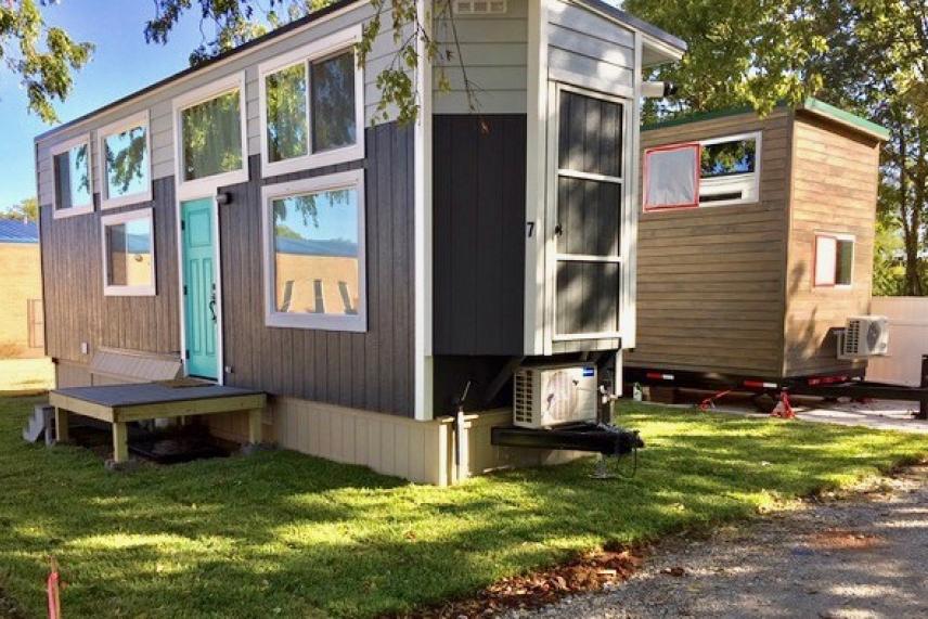 Two modern tiny houses on green grass, one with a turquoise door.