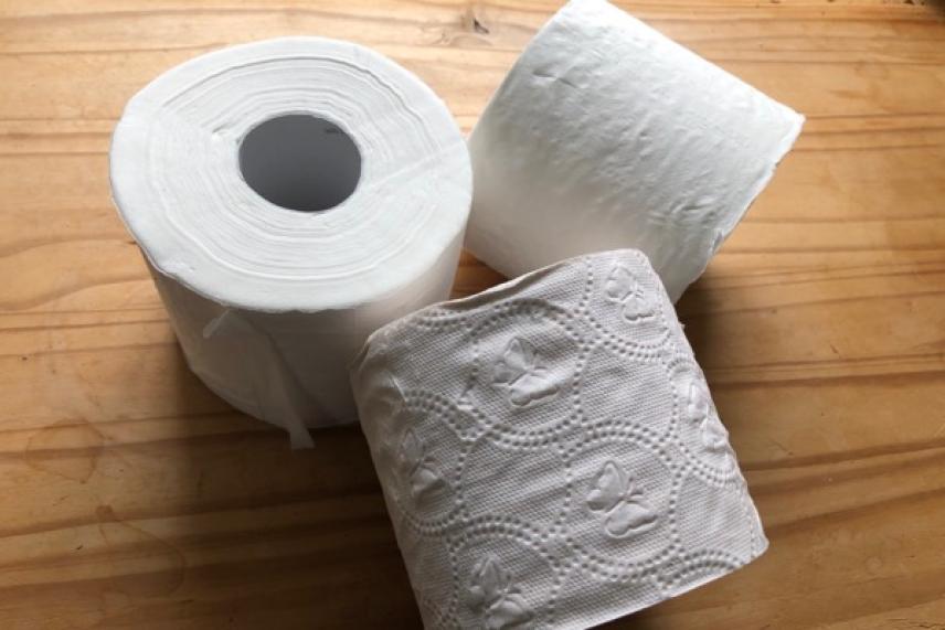 Three toilet paper rolls on a wooden surface.