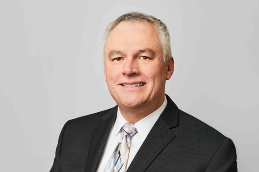 Smiling man in a suit and tie against a neutral background.