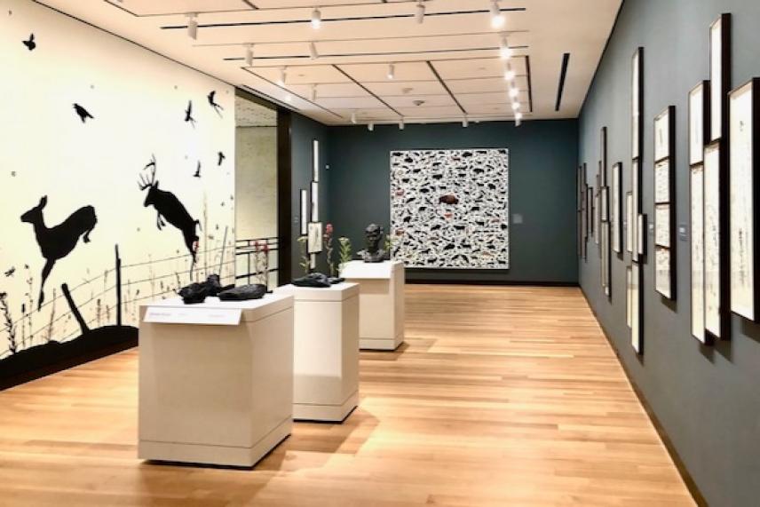 Art gallery with wall silhouettes of leaping animals and framed artworks.