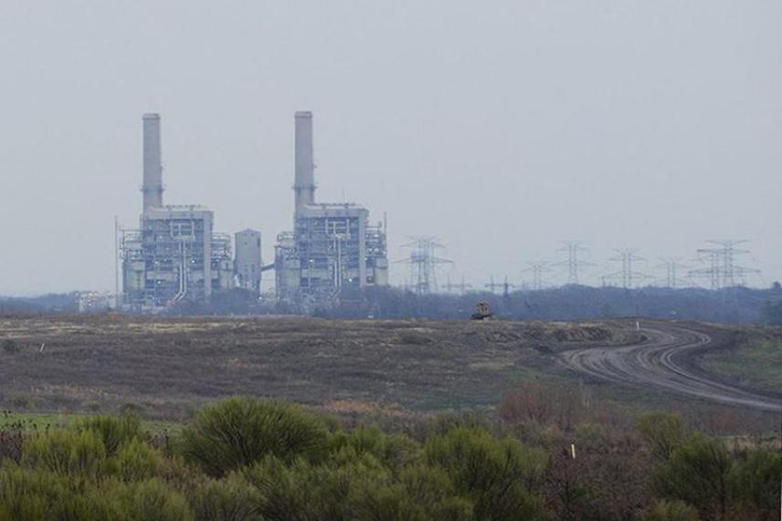 Power plant with smokestacks in a flat, open landscape.
