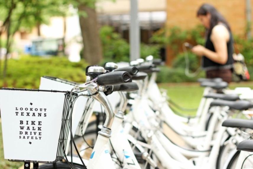 White rental bikes lined up; a person stands blurred in the background.